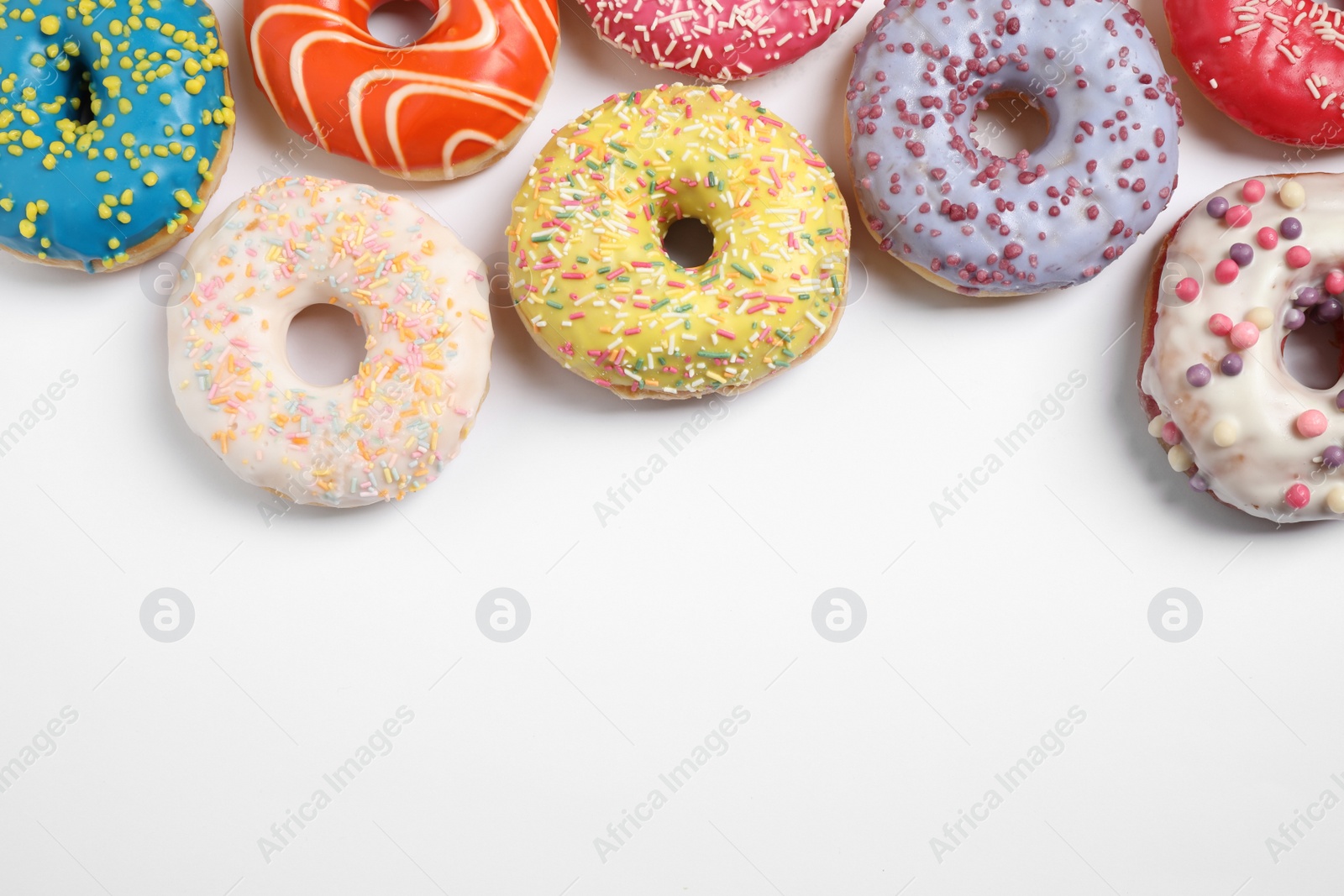 Photo of Delicious glazed donuts on white background, flat lay. Space for text