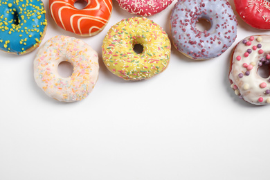 Photo of Delicious glazed donuts on white background, flat lay. Space for text