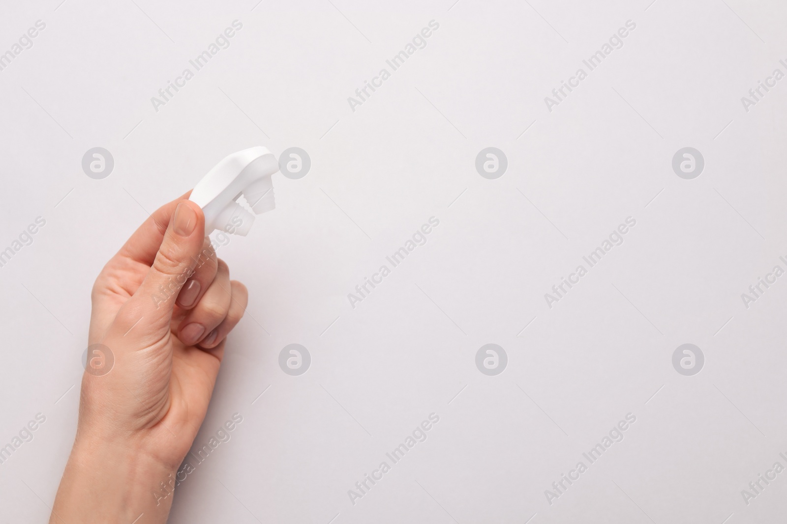 Photo of Woman holding anti-snoring device on light grey background, top view. Space for text