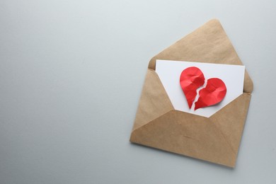 Photo of Broken heart. Envelope with halves of torn red paper heart on white background, top view. Space for text