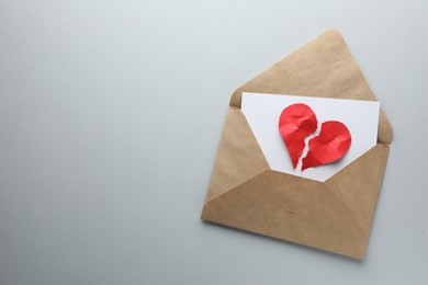 Broken heart. Envelope with halves of torn red paper heart on white background, top view. Space for text