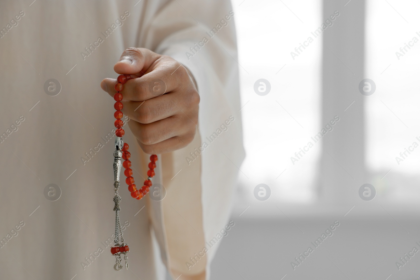 Photo of Muslim man with misbaha indoors, closeup. Space for text