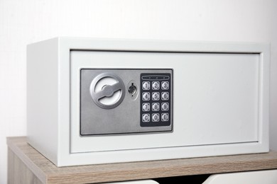 Photo of Closed steel safe on wooden table against white background