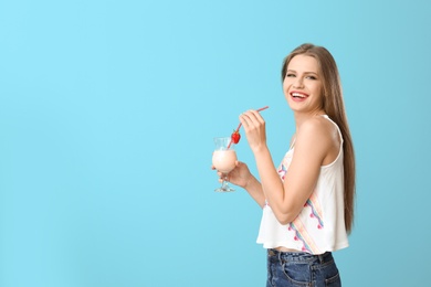 Photo of Young woman with glass of delicious milk shake on color background