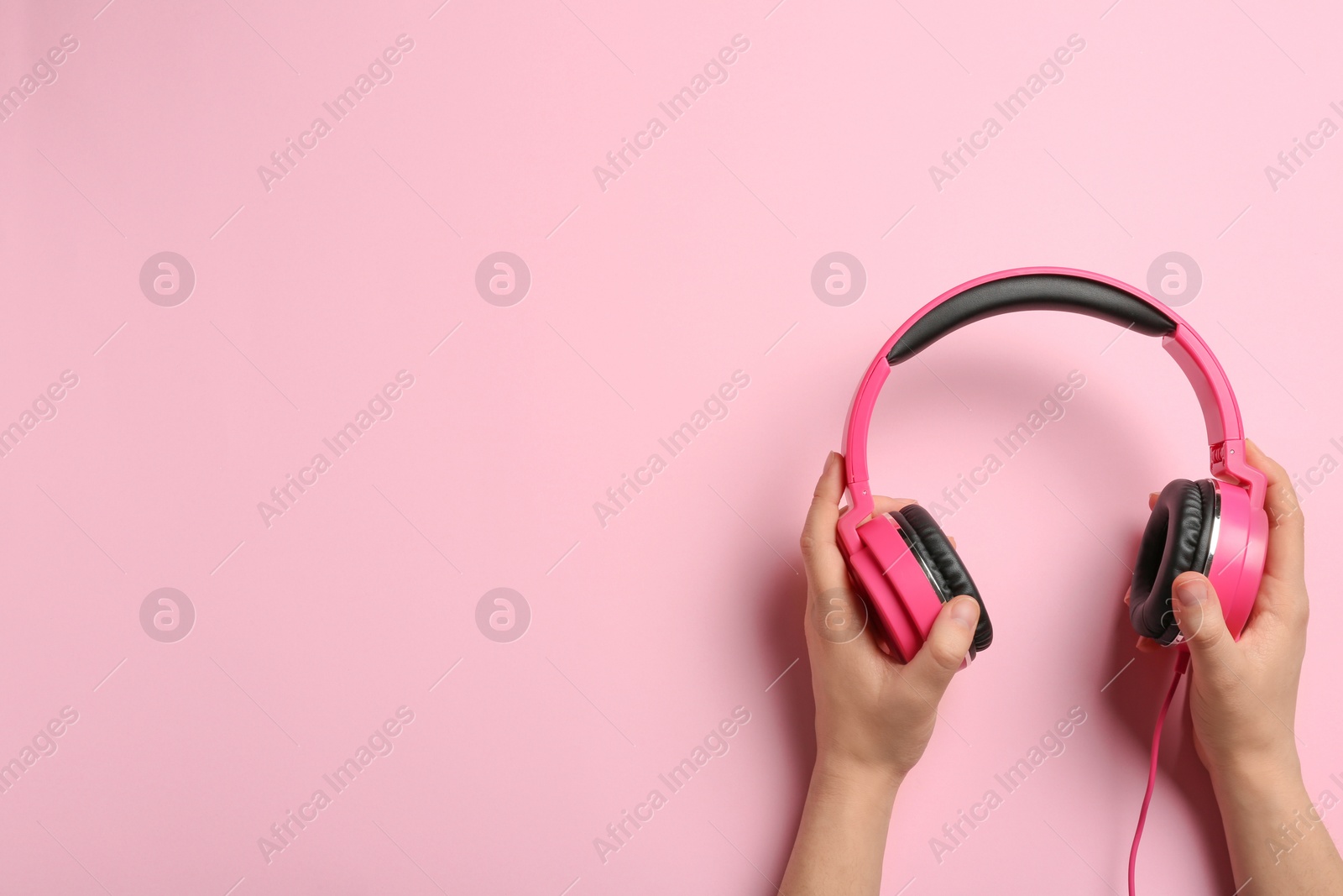 Photo of Woman holding stylish headphones on color background, closeup. Space for text