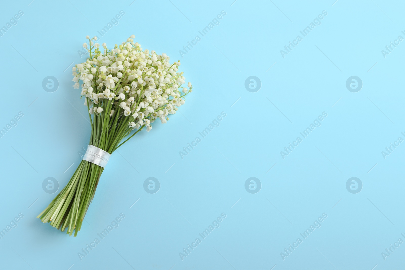 Photo of Beautiful lily of the valley bouquet on light blue background, top view. Space for text