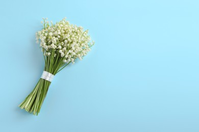 Beautiful lily of the valley bouquet on light blue background, top view. Space for text