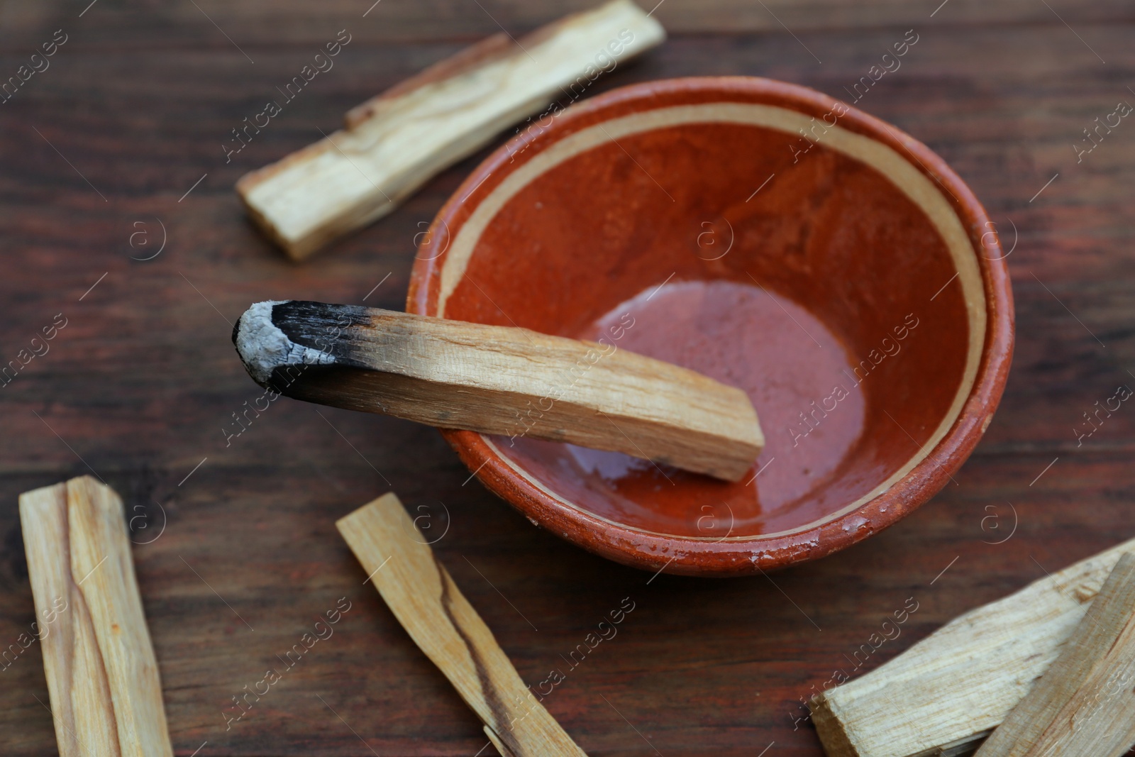 Photo of Palo santo sticks and bowl on wooden table