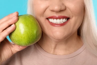 Photo of Smiling woman with perfect teeth and green apple on color background, closeup