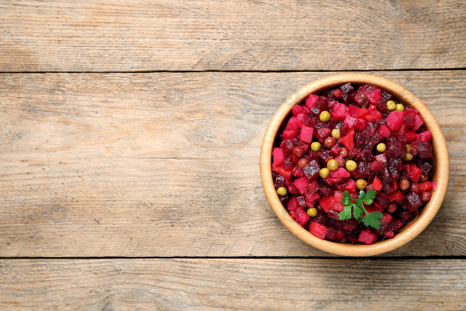 Photo of Traditional Russian vinaigrette salad on wooden table, top view. Space for text