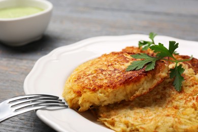 Tasty parsnip cutlets with parsley on grey wooden table, closeup