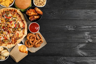 Photo of Pizza, onion rings and other fast food on black wooden table, flat lay with space for text
