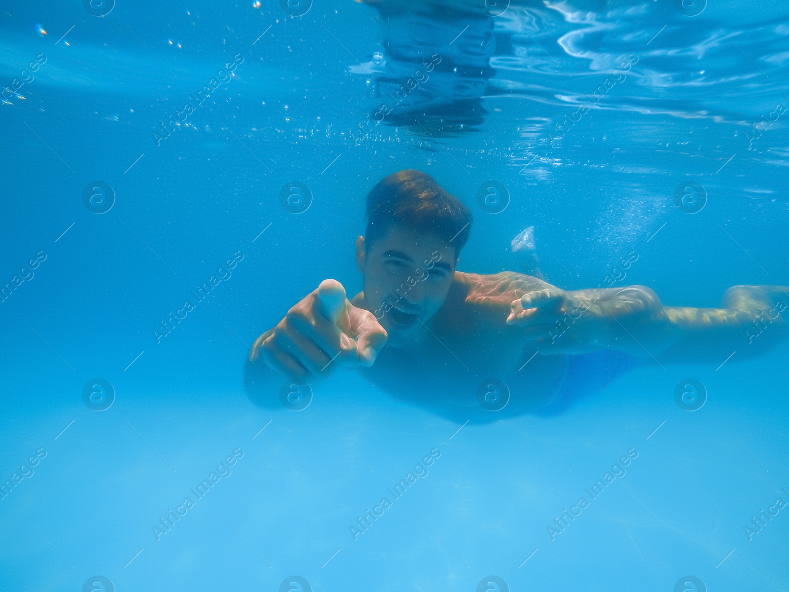 Photo of Handsome young man swimming in pool, underwater view