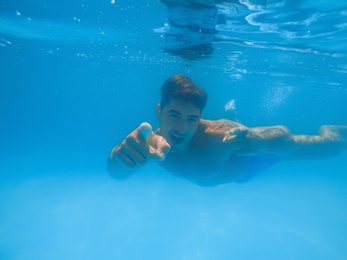 Handsome young man swimming in pool, underwater view