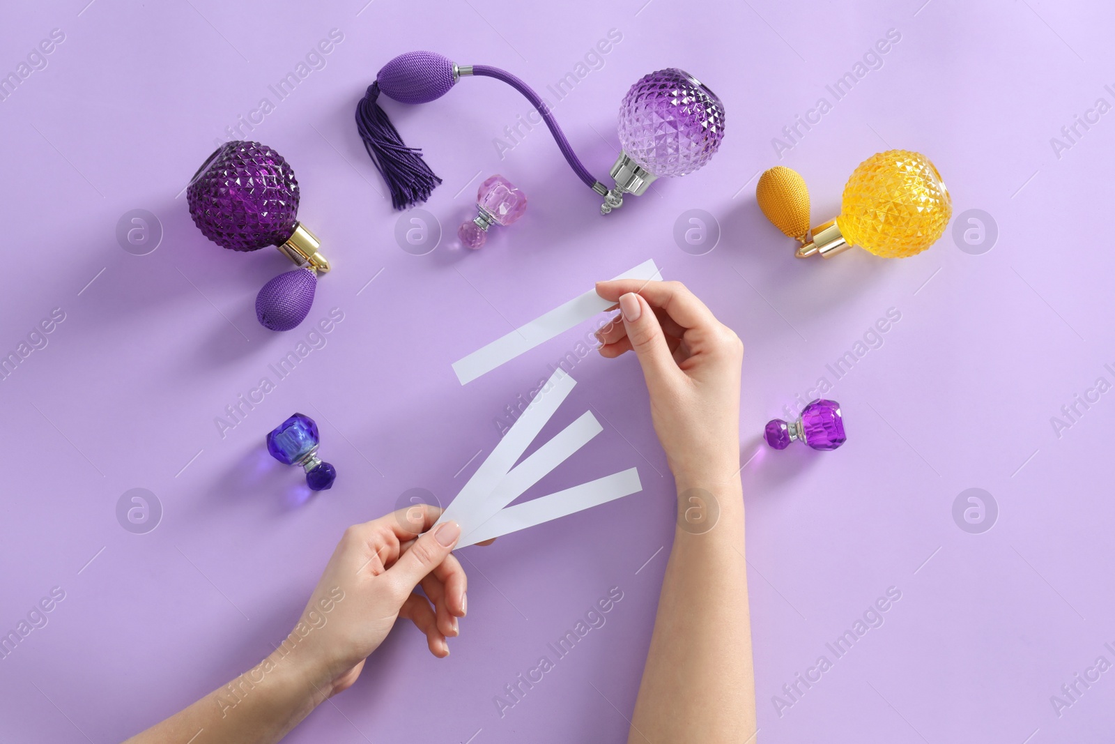 Photo of Woman with perfume blotters on violet background, top view