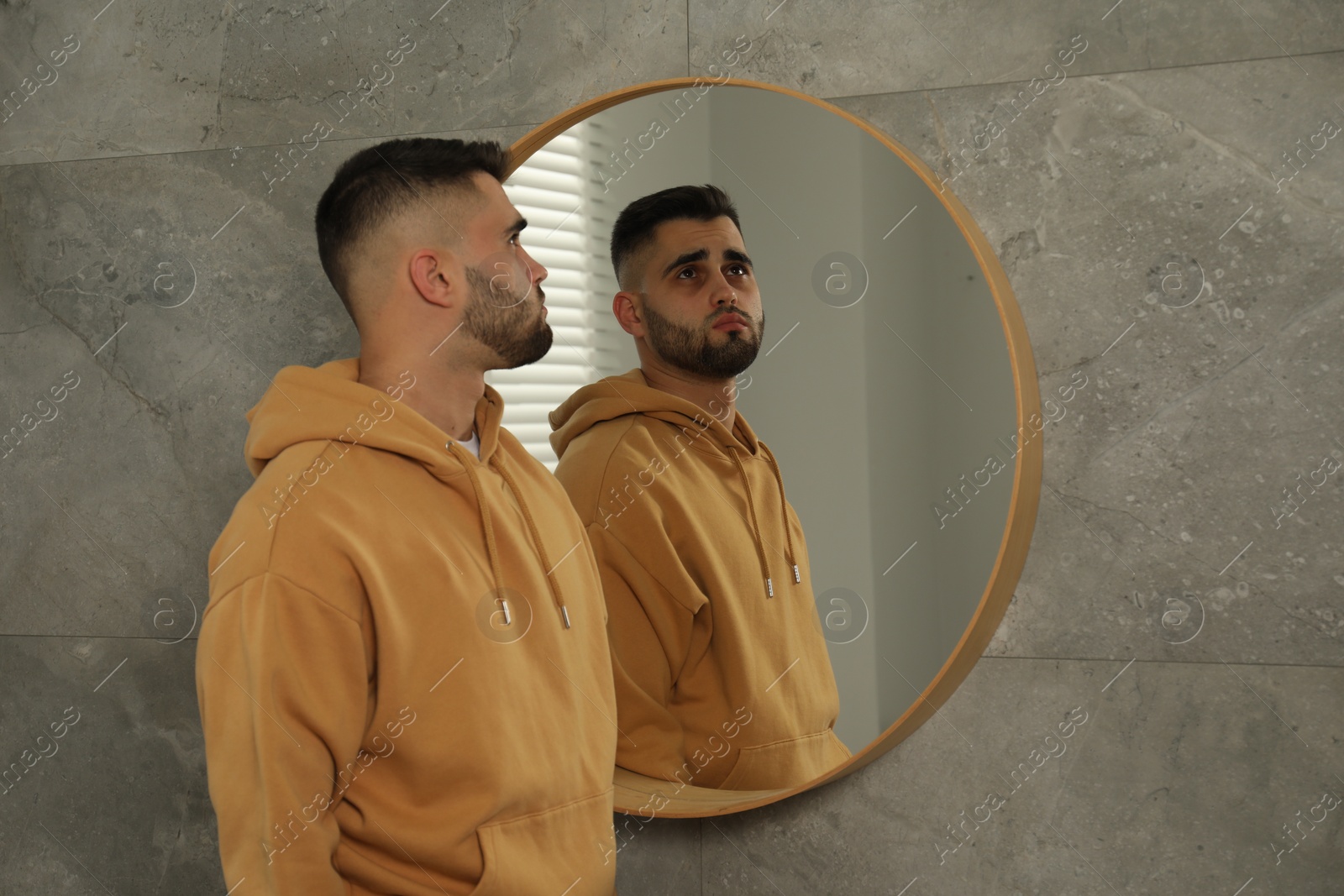 Photo of Sad young man near mirror at home