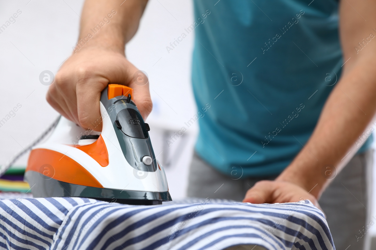 Photo of Man ironing shirt on board at home, closeup