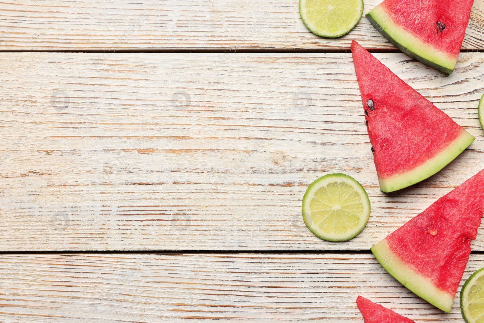 Photo of Tasty sliced watermelon and limes on white wooden table, flat lay. Space for text