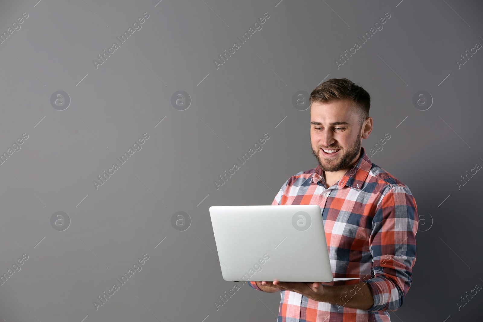 Photo of Young man with laptop on grey background