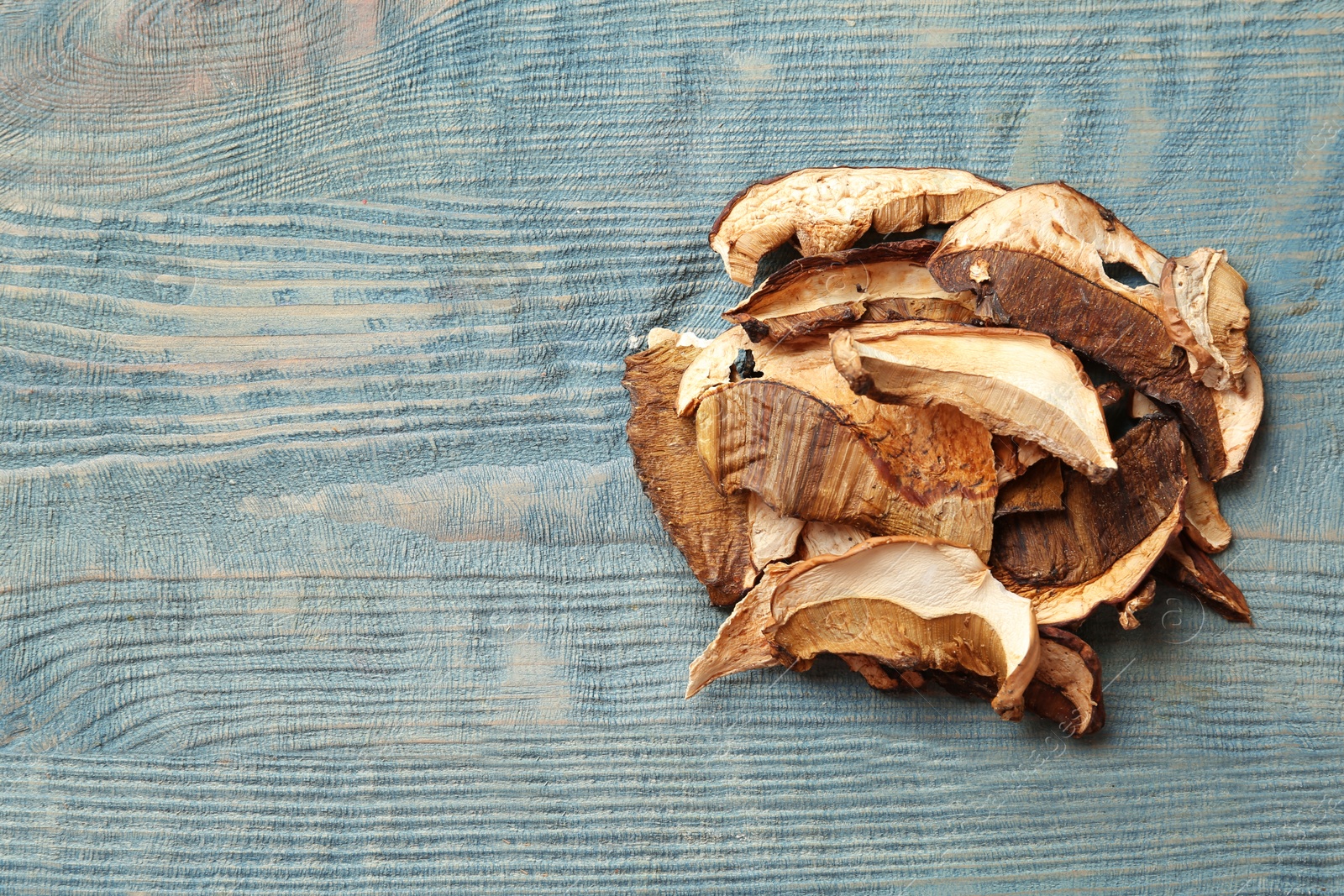 Photo of Delicious dried mushrooms on color wooden background, top view with space for text