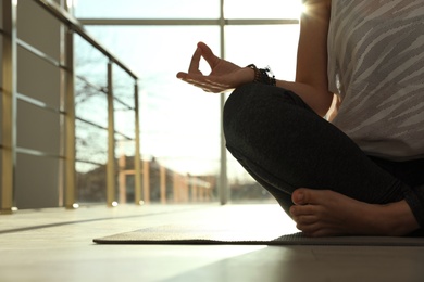 Photo of Young woman practicing yoga in sunlit room, closeup with space for text