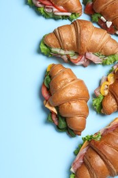 Photo of Croissant sandwiches on light blue background, flat lay