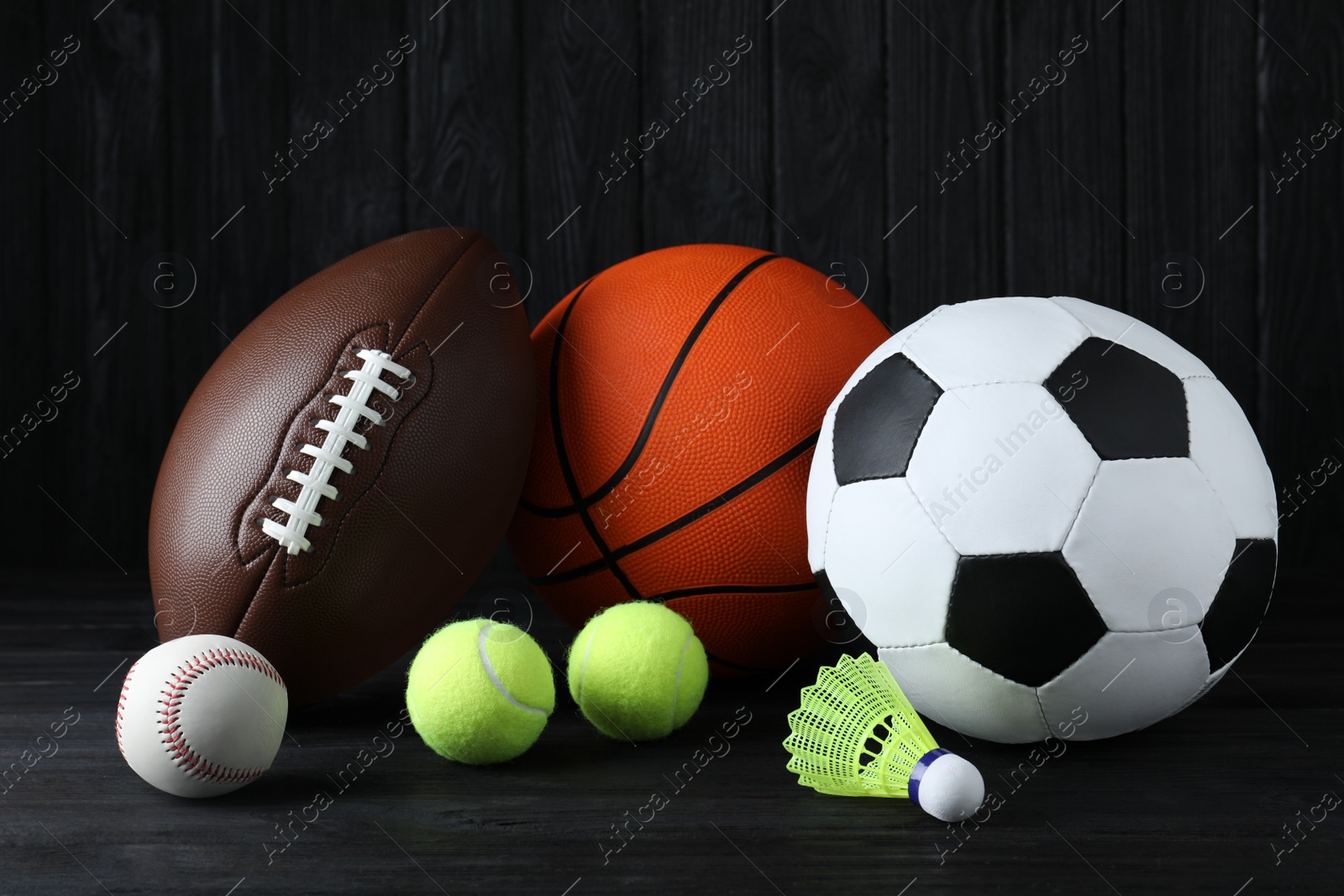 Photo of Set of different sport balls and shuttlecock on black wooden table
