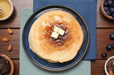 Delicious crepes with different products on wooden table, flat lay