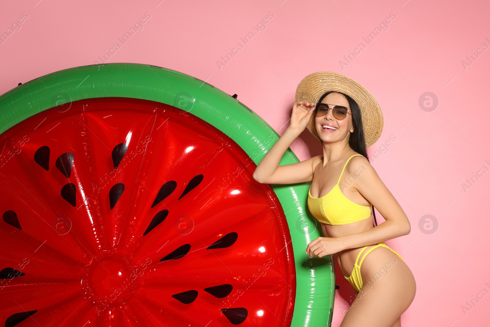 Photo of Young woman with stylish sunglasses near inflatable mattress against pink background