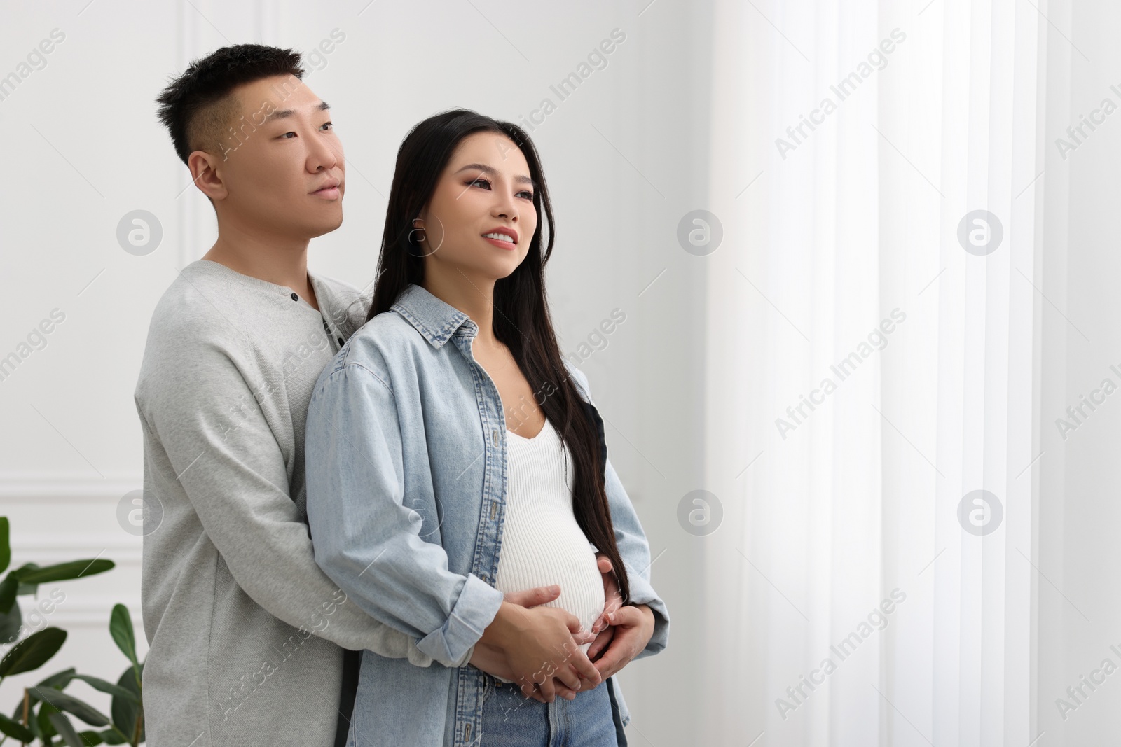 Photo of Man touching his pregnant wife's belly at home, space for text