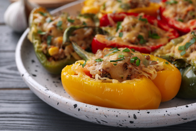 Photo of Tasty stuffed bell peppers on grey wooden table, closeup