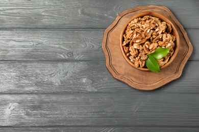 Dish with walnuts on wooden background, top view. Space for text