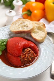 Photo of Delicious stuffed pepper served with basil and bread on white table, closeup