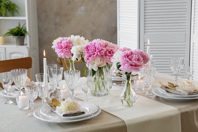 Photo of Stylish table setting with beautiful peonies and burning candles indoors