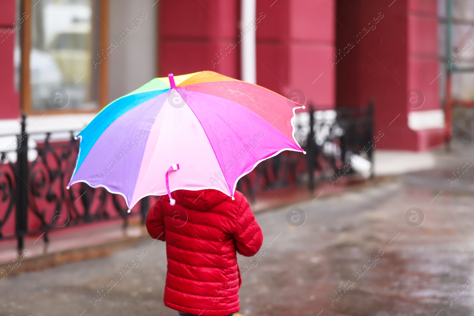 Photo of Little girl with umbrella in city on autumn rainy day