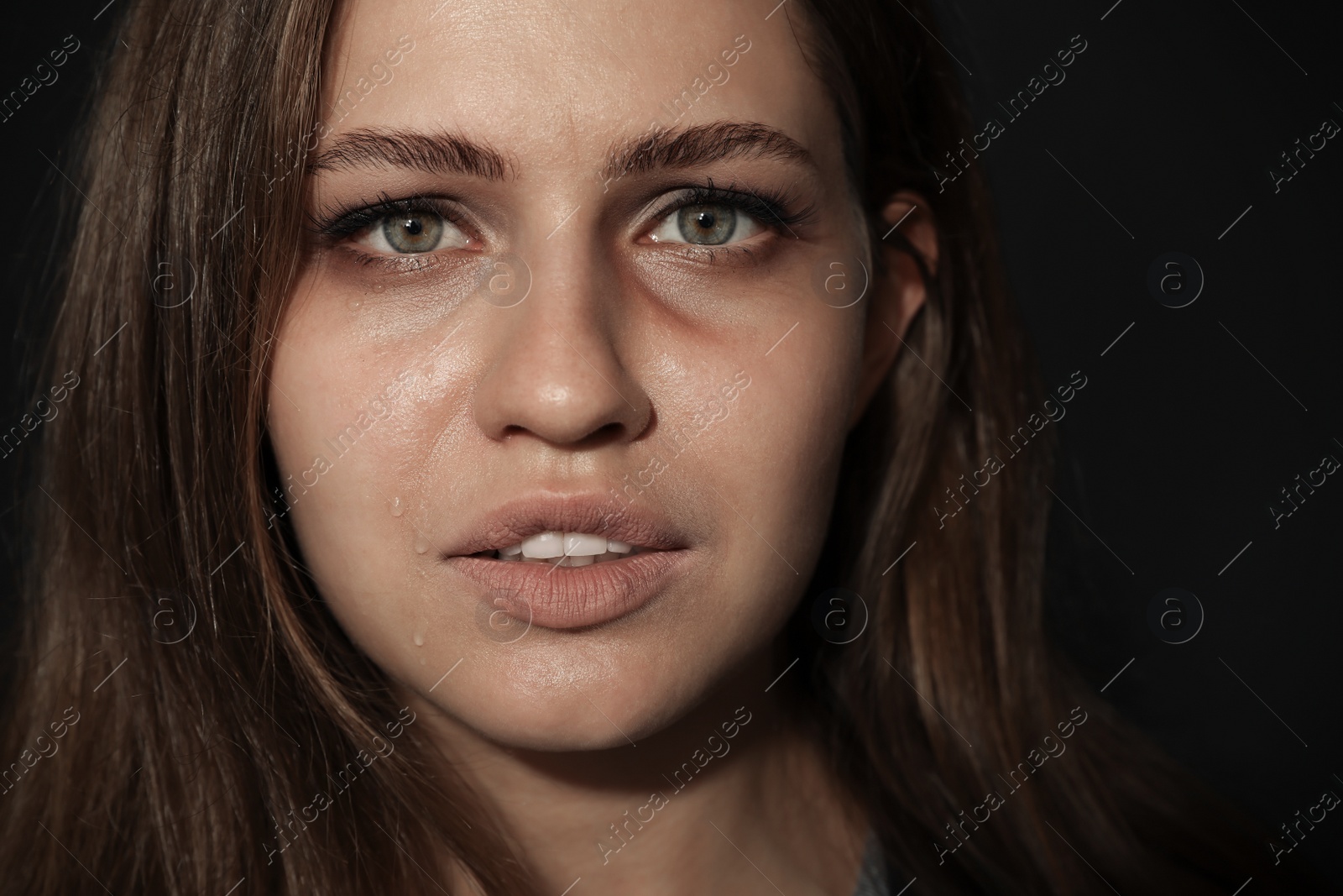 Photo of Crying young woman on dark background. Stop violence