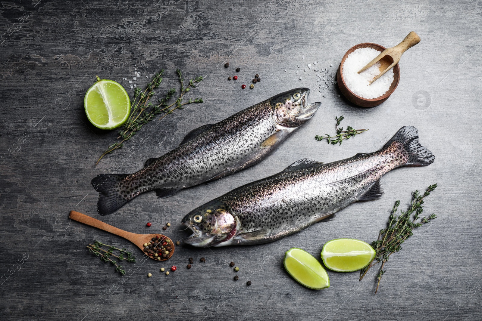 Photo of Flat lay composition with raw cutthroat trout fish on grey table