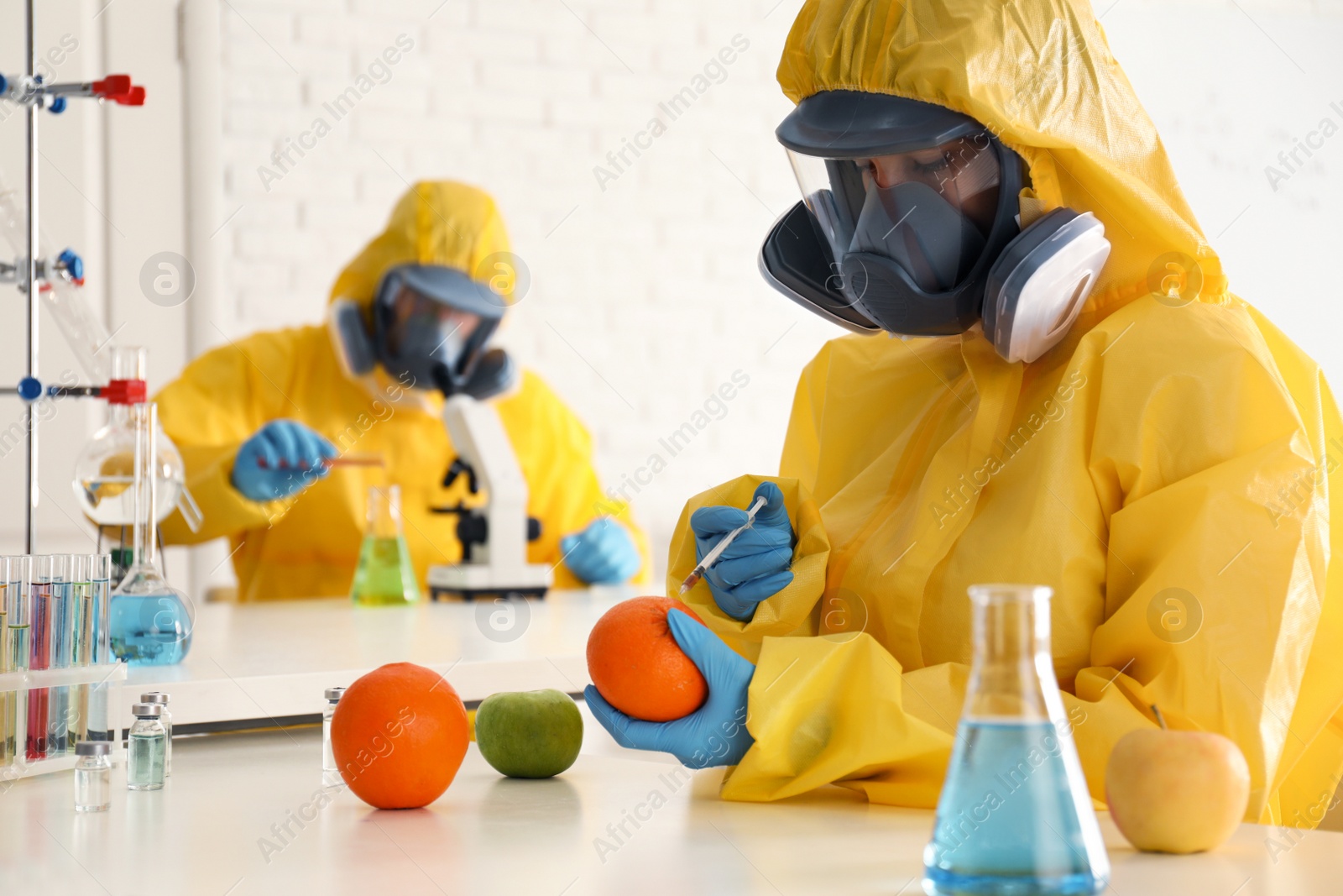 Photo of Scientist in chemical protective suit injecting orange at laboratory