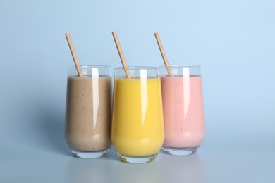Photo of Glasses with different smoothies on light blue background