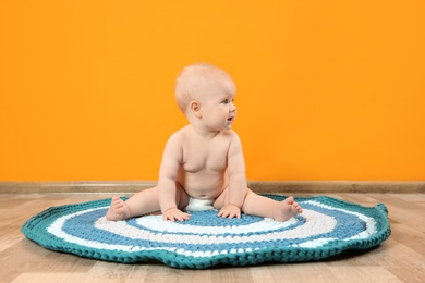 Cute little baby on soft rug near color wall