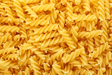 Photo of Uncooked fusilli pasta as background, closeup