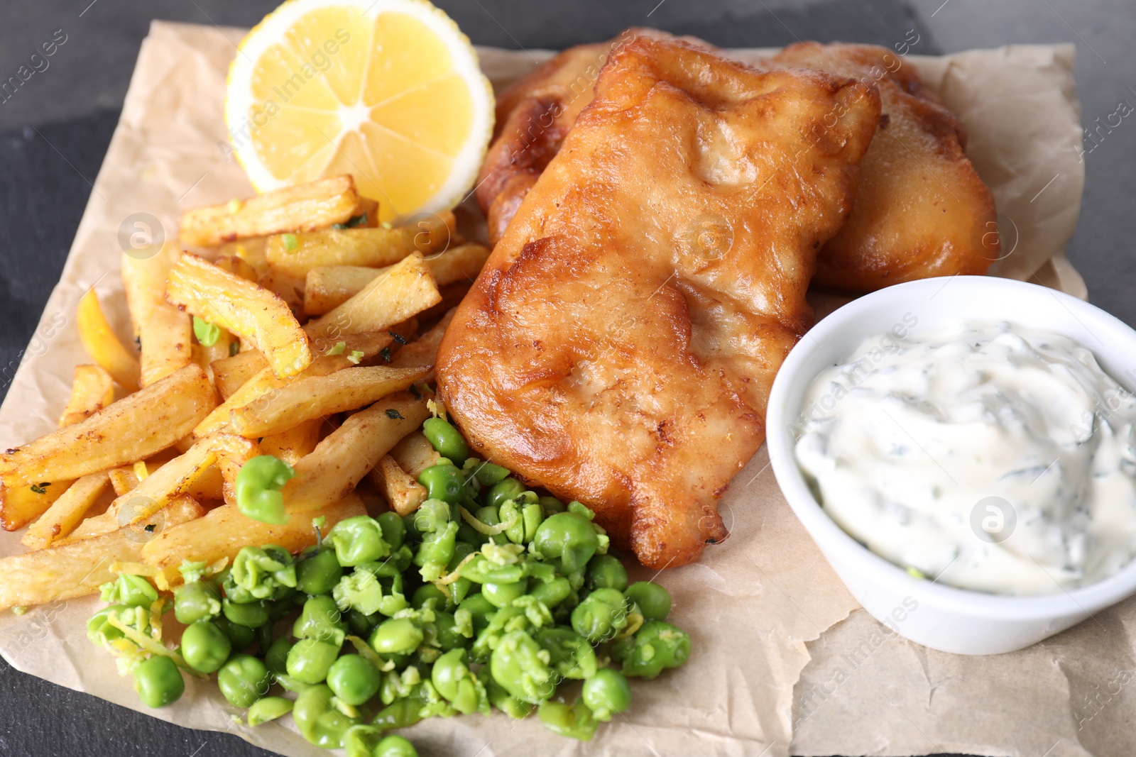 Photo of Tasty fish, chips, sauce and peas on table, closeup