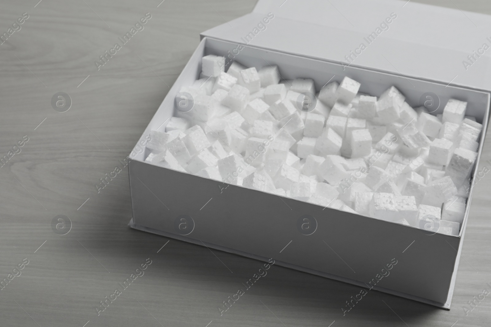 Photo of Cardboard box with styrofoam cubes on wooden floor