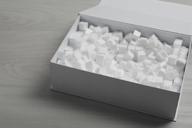 Cardboard box with styrofoam cubes on wooden floor