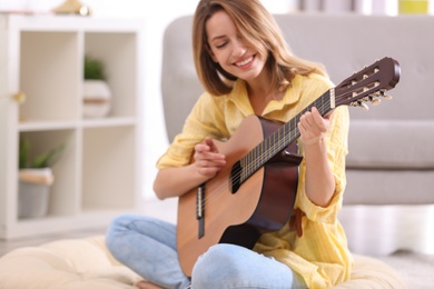 Photo of Young woman playing acoustic guitar at home
