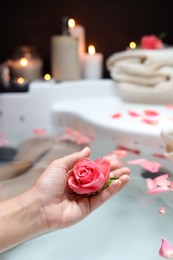 Photo of Woman holding rose flower while taking bath, closeup. Romantic atmosphere