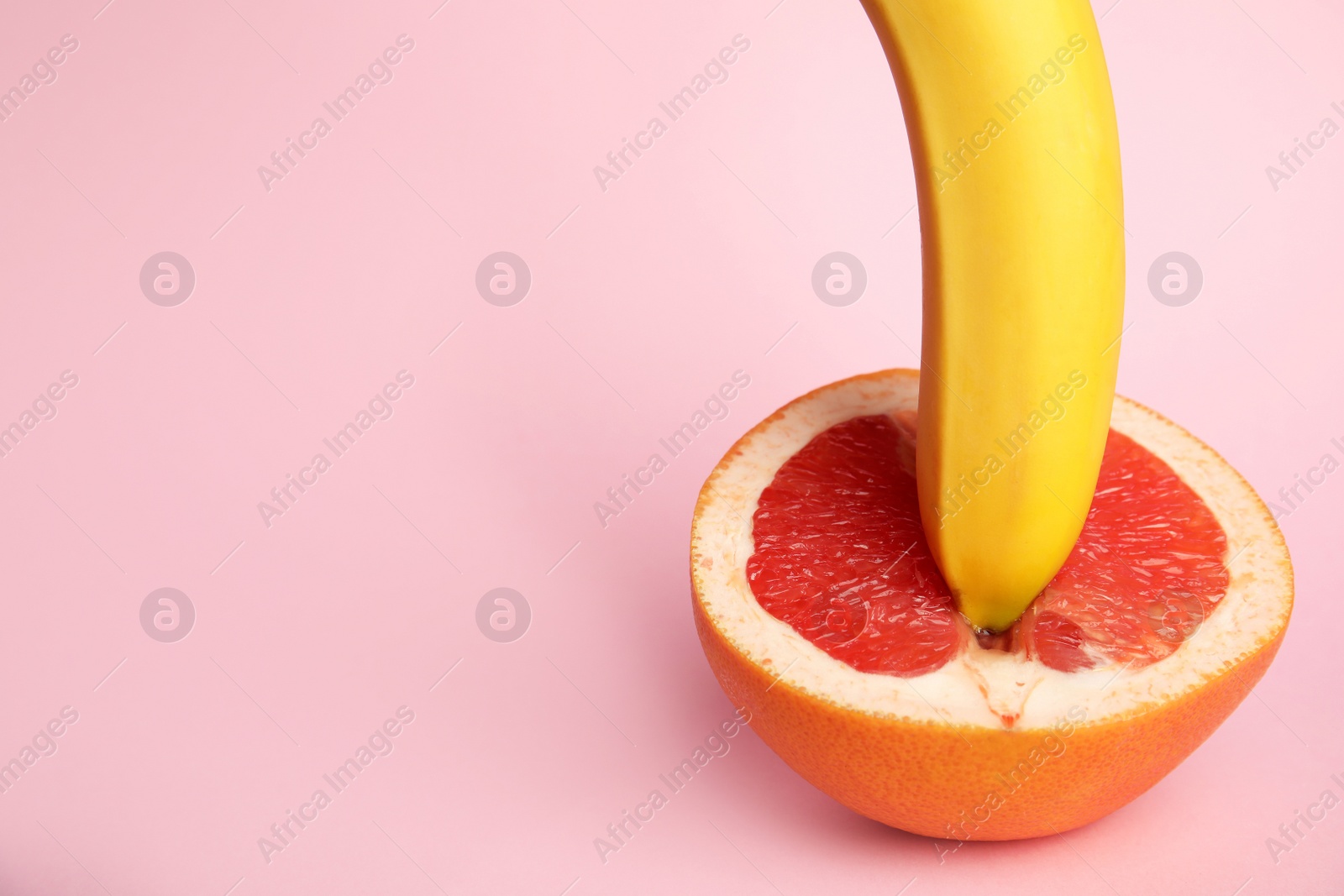 Photo of Fresh grapefruit and banana on pink background, space for text. Sex concept
