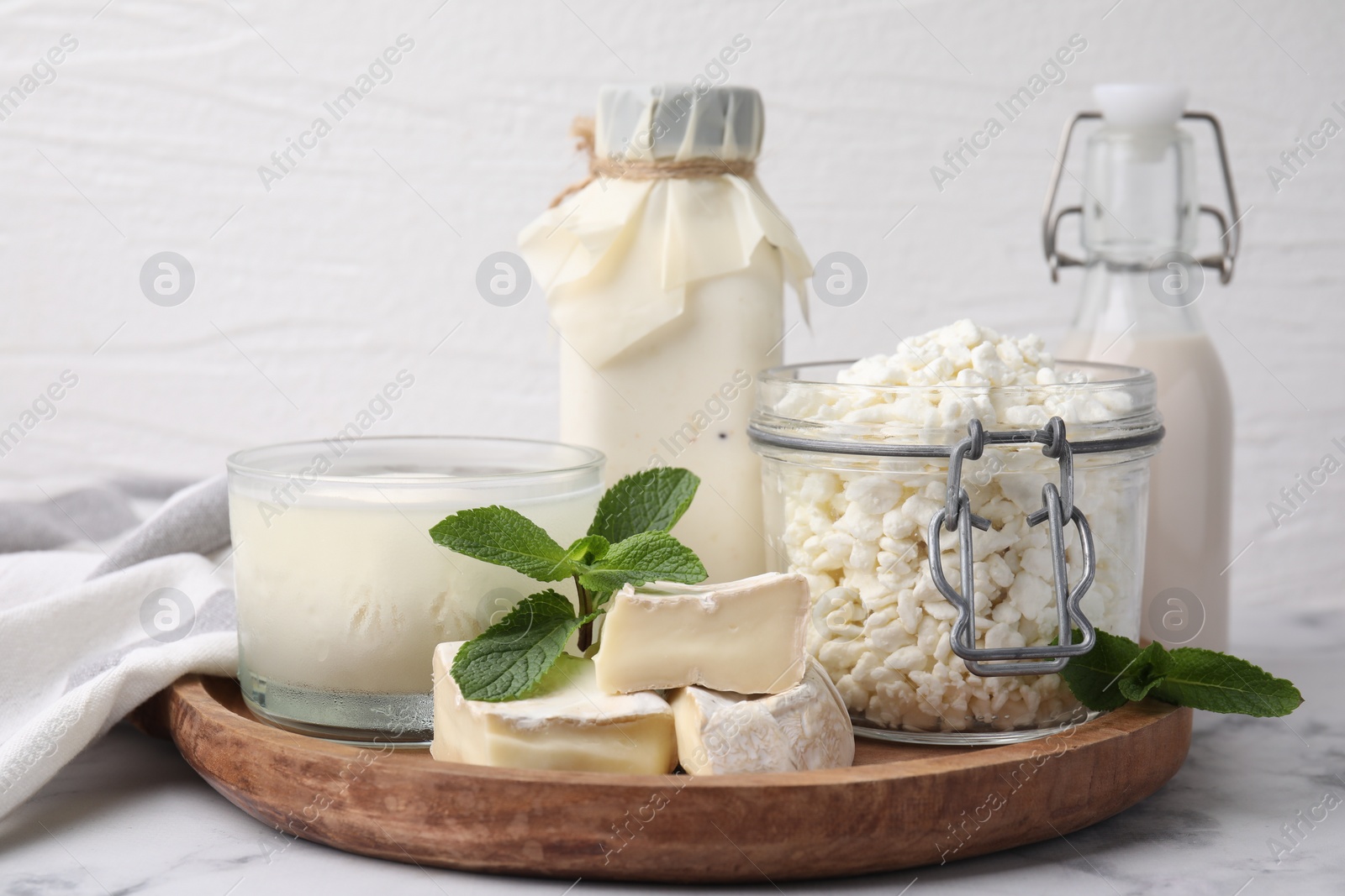 Photo of Different dairy products and mint on white marble table