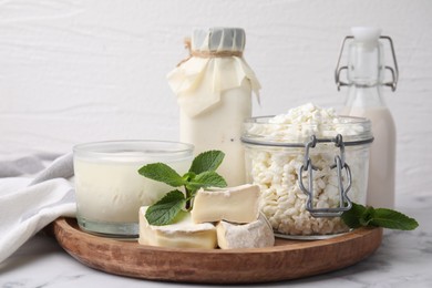 Different dairy products and mint on white marble table