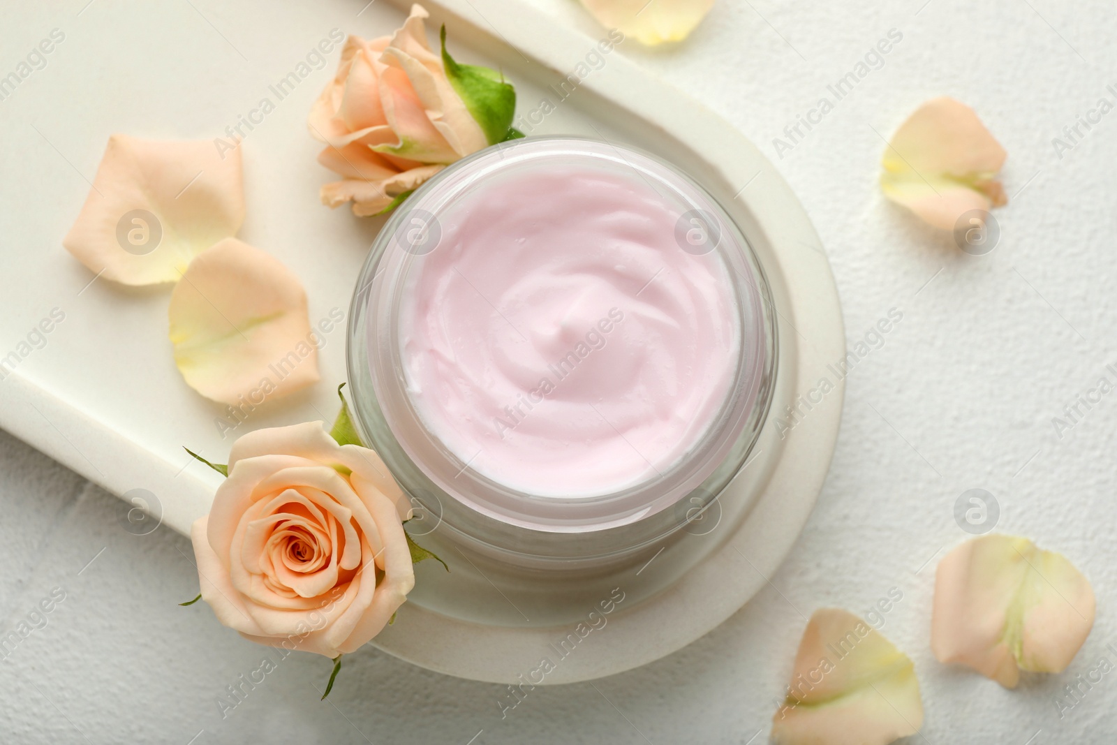 Photo of Jar of organic cream and roses on white table, flat lay